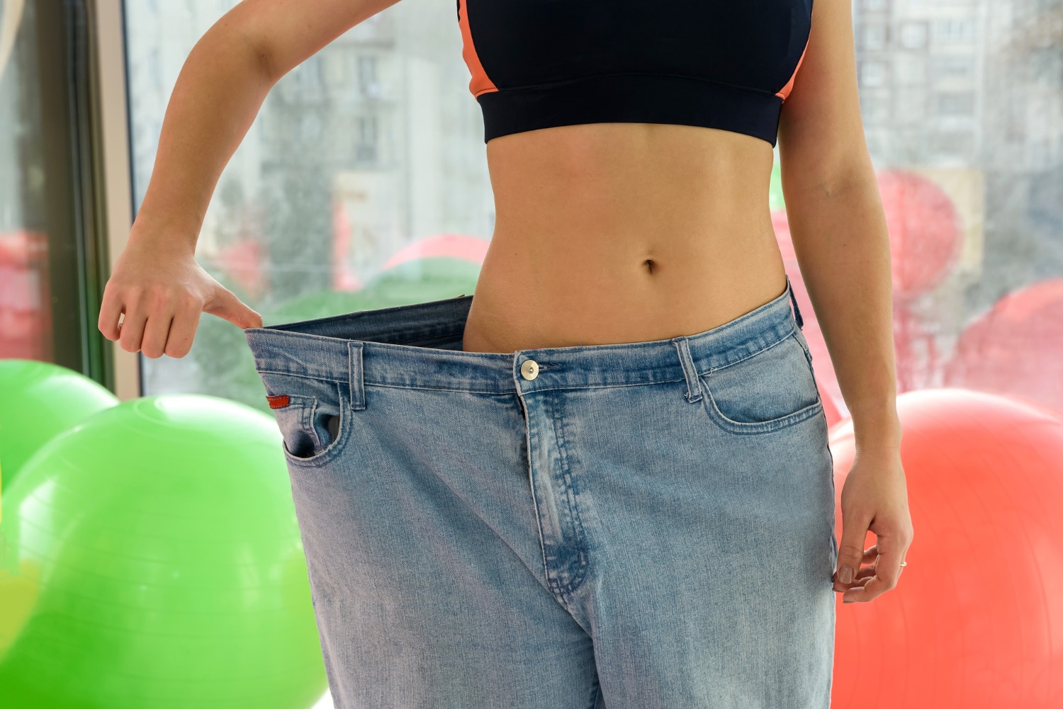 Egy fitneszteremben álló személy, aki bő ruháját mutatja fogyás után a Genheal Tirzepatide segítségével.